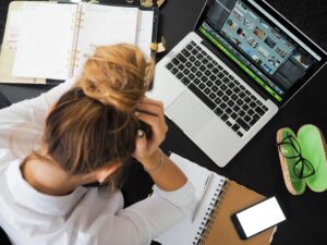 Mujer frente a su computadora agarrando su cabeza como signo de estrés. Aludiendo que estoy provoca la doble presencia.