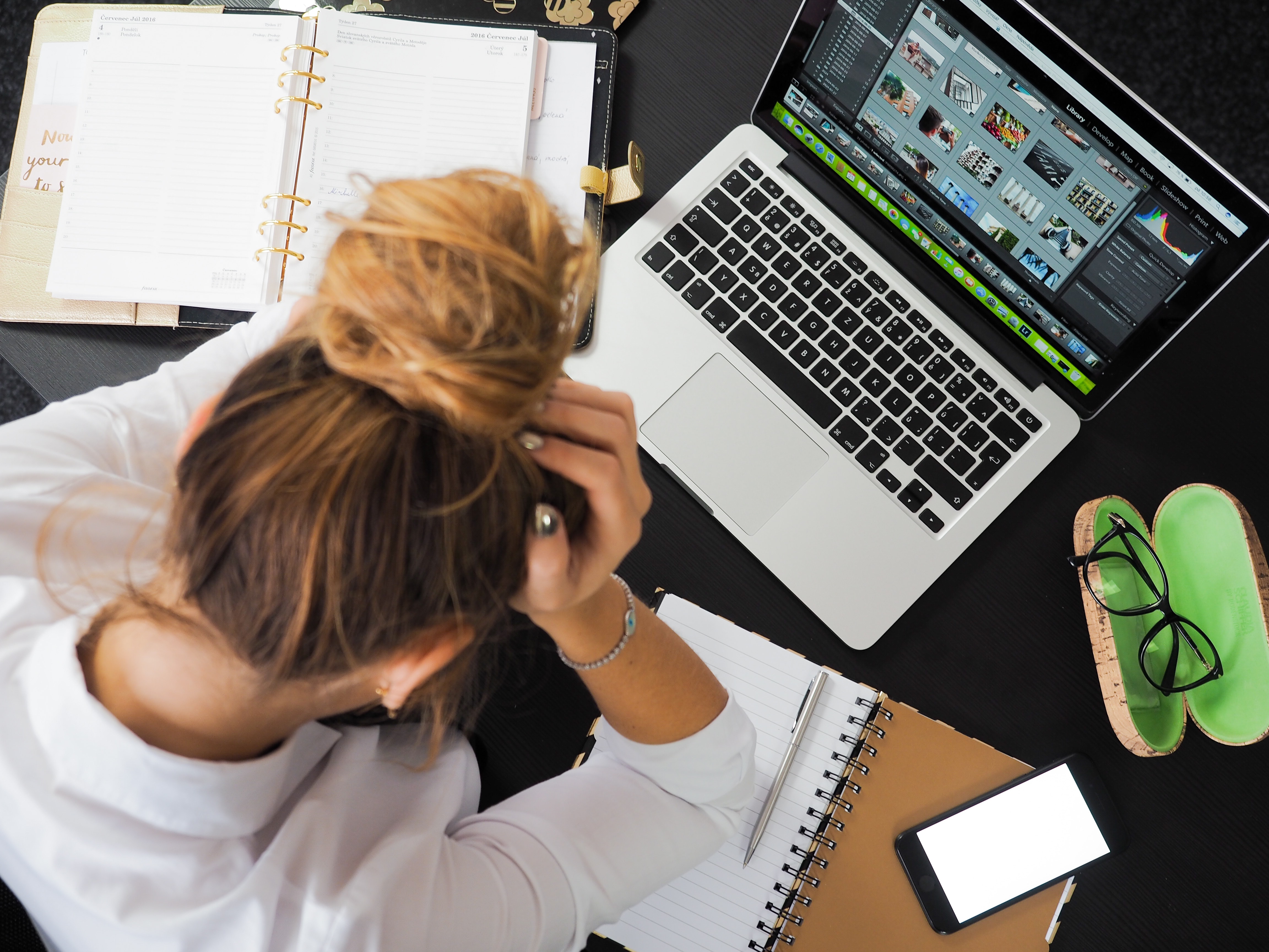 mujer frente a su computadora agarrando su cabeza
