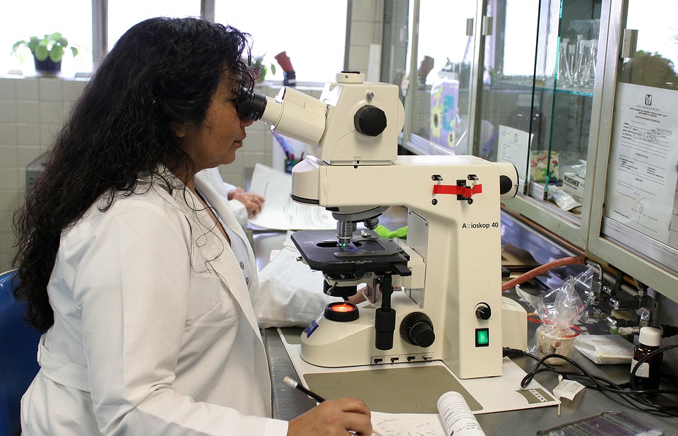 Científica trabajando en un laboratorio con un microscopio. La idea es repreentar a las mujeres en la ciencia.
